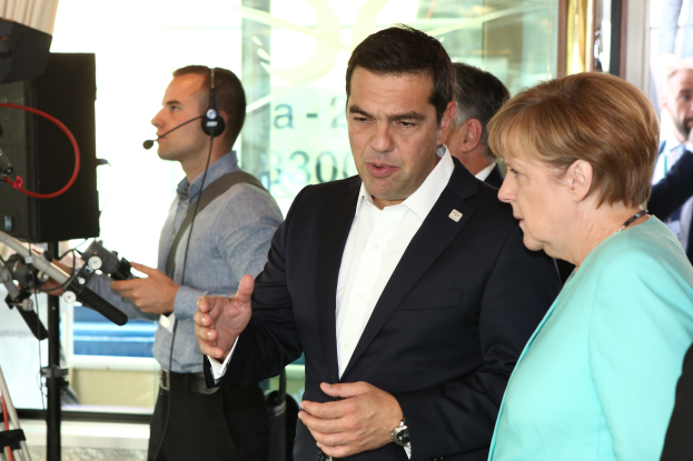 Bundeskanzlerin Angela Merkel und Bundeskanzler Joachim Gauck in Anzügen, die vor einer Glaswand mit Vorhang sprechen.