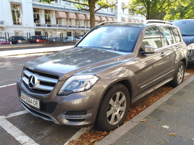 Ein Mercedes-Benz GLK 350 CDI BlueEfficiency Avantgarde fährt auf einer Straße mit Bäumen und Gebäuden mit Fenstern im Hintergrund.