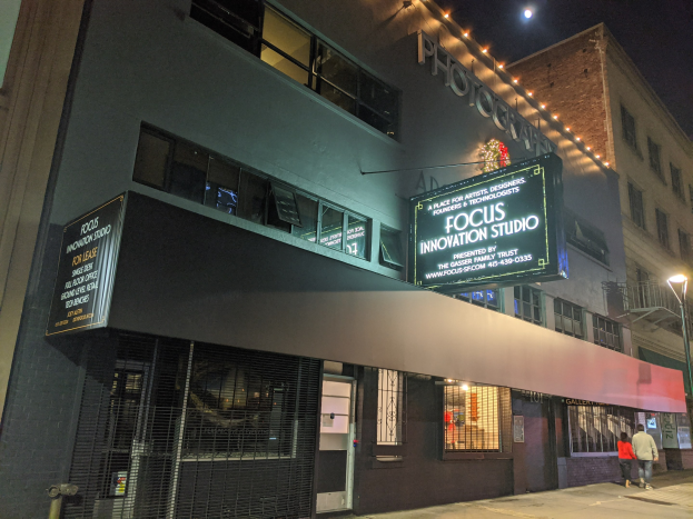 Außenansicht des Focus Innovation Studios in New York City bei Nacht, mit beleuchteten Gebäuden, Menschen auf dem Gehweg und sichtbarem Himmel.