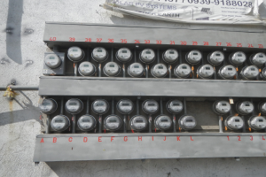 Nahaufnahme eines Elektrizitätszählers, der an der Seite eines Gebäudes montiert ist, mit einem Banner, das oben Text anzeigt.