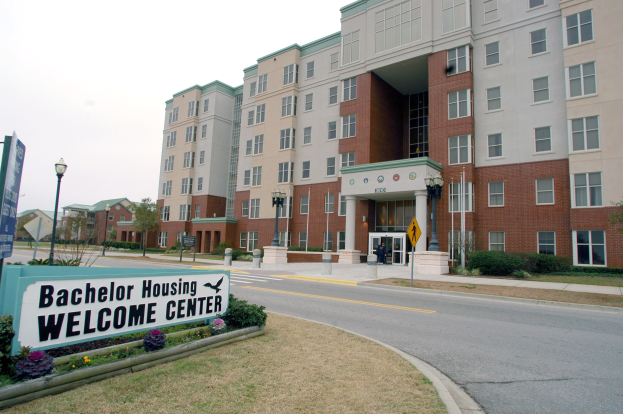 Außenansicht eines Bachelor-Wohnheim-Willkommenszentrums mit Gebäuden, Straßeninfrastruktur, Fahrzeugen, Grünflächen und einem klaren Himmel.