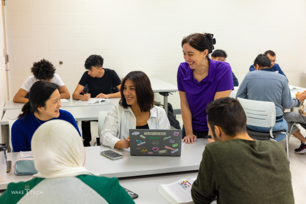 Gruppe von Menschen in einem Klassenzimmer, die über Klimawandel diskutieren, mit Laptops, Büchern und anderen Gegenständen auf dem Tisch.