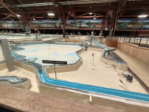 Großer Indoor-Wasserpark mit mehreren Wasserrutschen, Deckenbeleuchtung, Wandgemälde und Minigolfplatz.