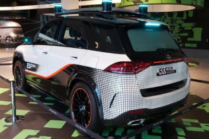 Mercedes-Benz E-Klasse Electric SUV auf der IAA in Frankfurt gezeigt, umgeben von Absperrpollern mit Seilen und Lichtern, mit einem weiteren Fahrzeug und Text an einer Wand im Hintergrund.