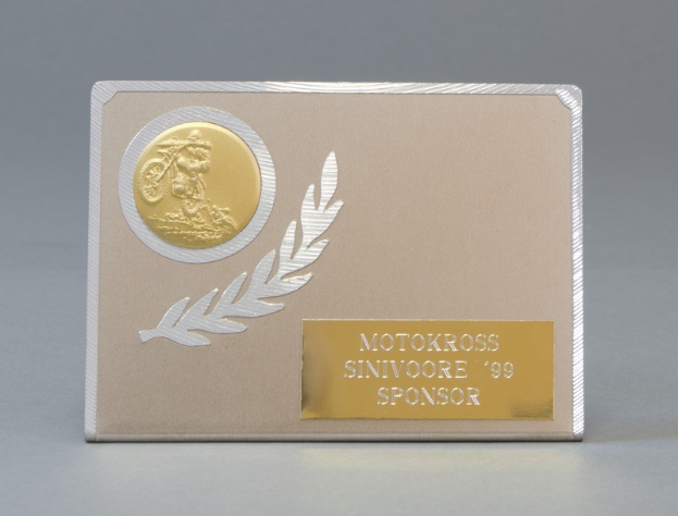 Eine goldene und silberne Visitenkarte mit einem Lorbeerkranz-Design, mittig im Bild platziert, mit Text, der wahrscheinlich den Namen des Sponsors darstellt.