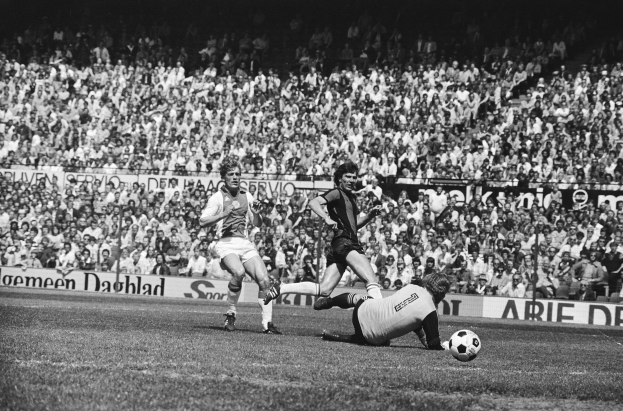 Schwarzes Foto von Männern, die auf einem Feld Fußball spielen, mit Zuschauern im Hintergrund und einer Bundesliga 1978-79 Ajax 1-1 Hannover 96-Tafel.
