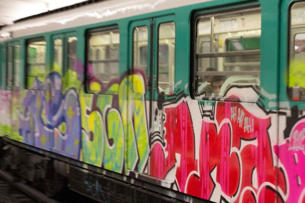 Ein Zug auf einem Bahngleis mit zwei Personen darin und Graffiti an seiner Außenseite.