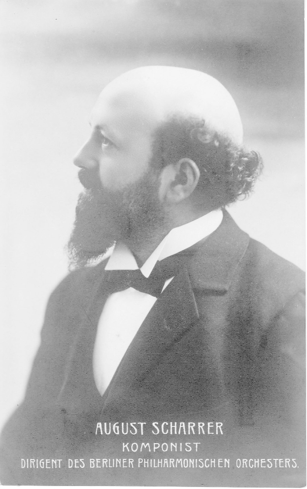 Schwarzes und weißes Porträt von August Scharrer, einem deutschen Komponisten, der einen Blazer und eine Krawatte trägt, mit Text unten.