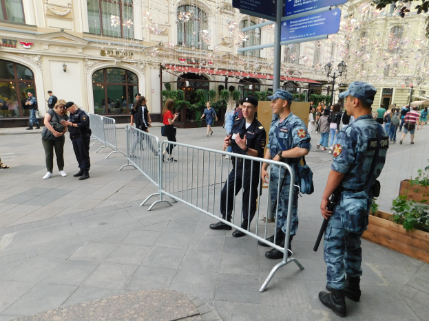 Polizeibeamte in Uniform stehen vor einer Menge, einige halten Waffen, mit Absperrungen und Schildern im Vordergrund und Gebäuden, Bäumen und Laternen im Hintergrund während eines Anti-Terror-Einsatzes in Wien, Österreich.
