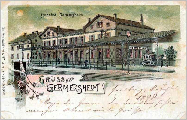 Schwarz-weiß-Postkarte des Bahnhofs Germersheim in Deutschland, zeigt ein Bahnhofsgebäude, Menschen, Fahrzeuge, Bäume, einen Zaun, einen Laternenpfahl und einen bewölkten Himmel.