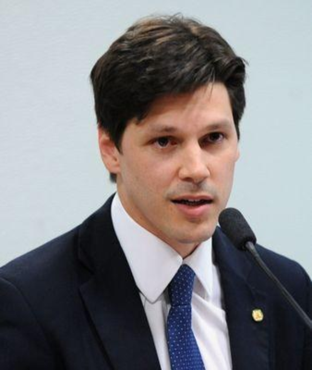 Ein Mann im Anzug spricht in ein Mikrofon, wahrscheinlich um die Genehmigung eines Gesetzes durch die Regierung zu verkünden.