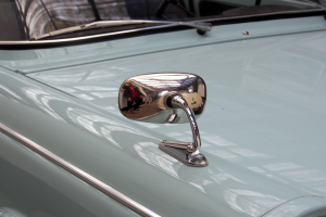 Ein Nahaufnahme eines Autos Seitenspiegels, der am Fahrzeug befestigt ist und die Umgebung reflektiert, gibt dem Auto ein elegantes und modernes Aussehen.