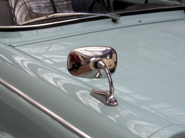 Ein Nahaufnahme eines Autos Seitenspiegels, der am Fahrzeug befestigt ist und die Umgebung reflektiert, gibt dem Auto ein elegantes und modernes Aussehen.