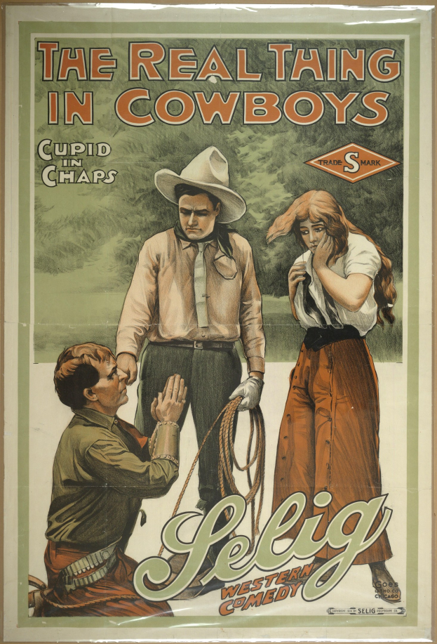 Plakat an einer Wand mit drei Personen, zwei Männer mit Cowboyhüten und eine Frau in einem langen Kleid, mit der Aufschrift "The Real Thing in Cowboys" in fetter schwarzer Schrift auf einem hellgelben Hintergrund.