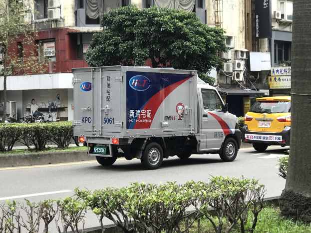 Ambulanz auf der Straßenseite neben einem Baum mit Fahrzeugen, Gebäuden und anderen Objekten im Hintergrund.