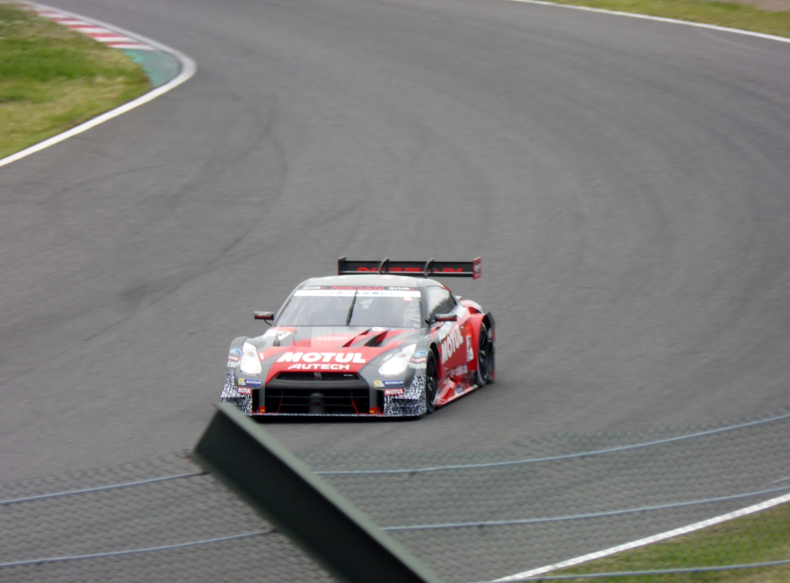 Ein Nissan GT-R Nismo GT3-Rennwagen auf der Nürburgring 24 Stunden-Strecke, flankiert von grünem Gras.