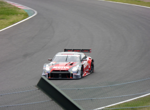Ein Nissan GT-R Nismo GT3-Rennwagen auf der Nürburgring 24 Stunden-Strecke, flankiert von grünem Gras.